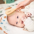 Niemowlę leżące na plecach, czesane miękką szczotką Babyono 799 z naturalnym włosiem kozim i drewnianą rączką